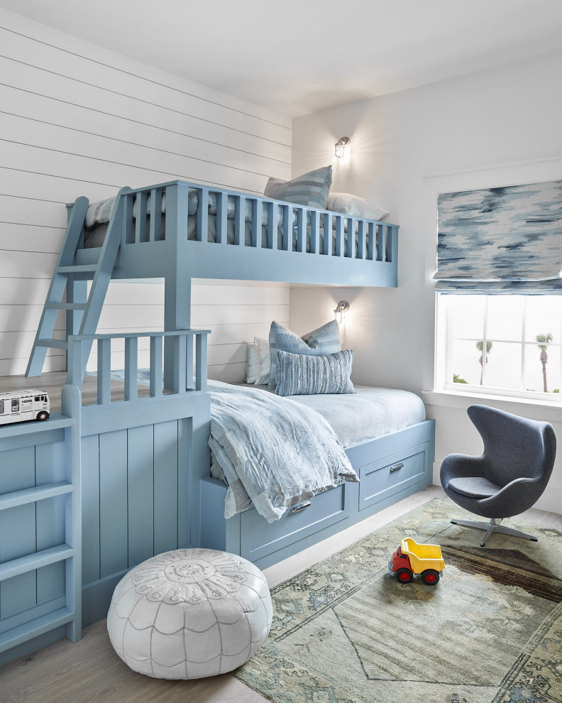 Diseño de dormitorio infantil de 4 a 10 años costero de tamaño medio con paredes blancas, suelo de madera clara y suelo blanco