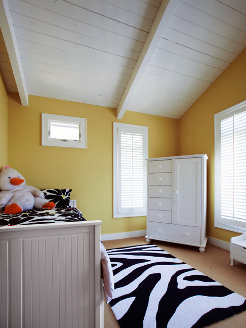 Immagine di una piccola cameretta per bambini da 4 a 10 anni classica con pareti gialle, moquette e pavimento beige