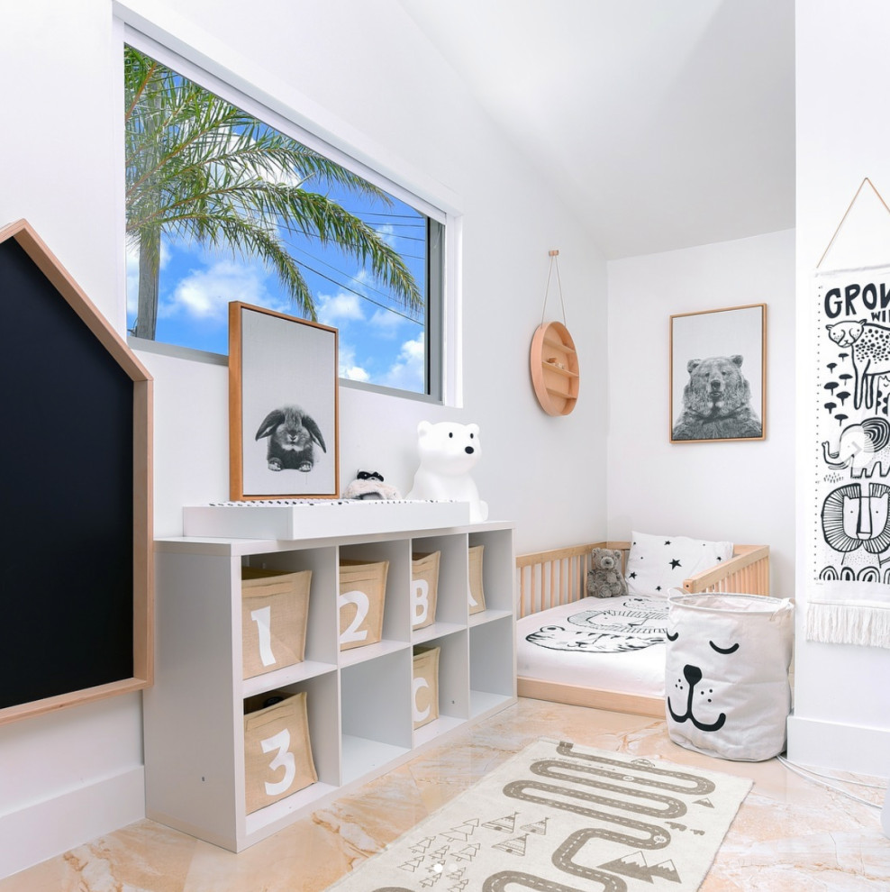 This is an example of a medium sized coastal toddler’s room for boys in Miami with white walls and beige floors.