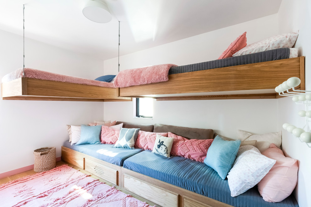 Modelo de dormitorio infantil actual de tamaño medio con paredes blancas, suelo de madera en tonos medios y suelo marrón
