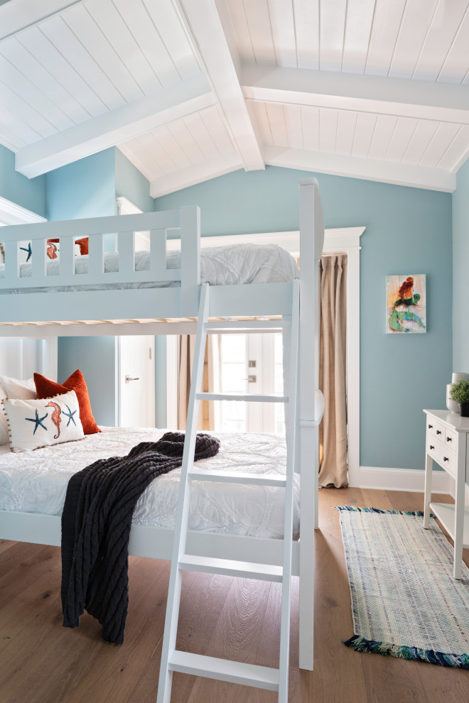 Modelo de dormitorio infantil marinero de tamaño medio con paredes azules, suelo de madera en tonos medios, suelo beige y madera