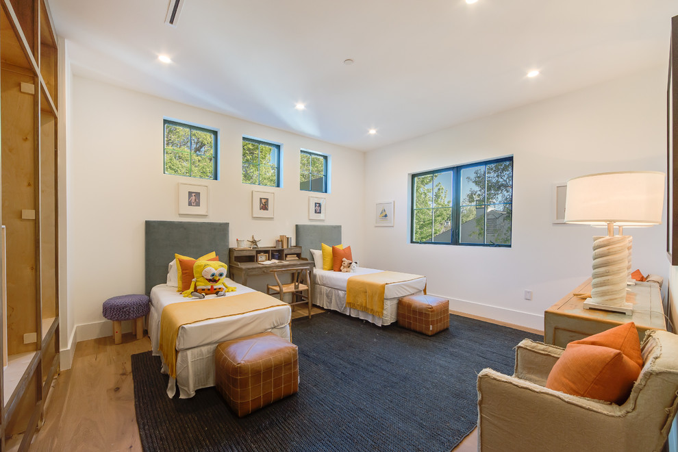 Medium sized classic gender neutral children’s room in Los Angeles with white walls, light hardwood flooring and brown floors.