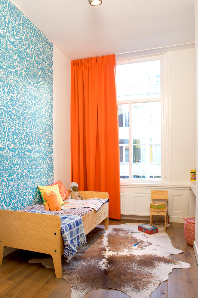 Aménagement d'une chambre d'enfant de 4 à 10 ans scandinave avec un mur bleu et un sol en bois brun.