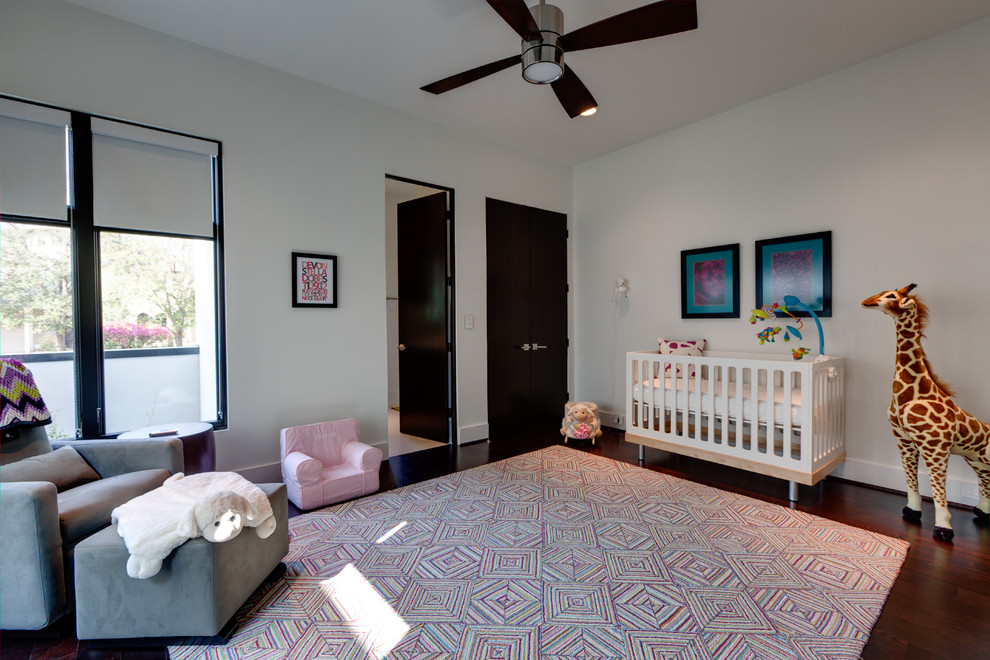 Modern inredning av ett stort barnrum kombinerat med sovrum, med vita väggar, mörkt trägolv och brunt golv