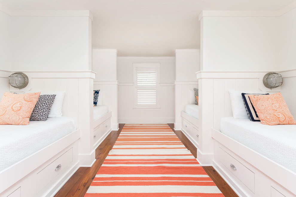 Diseño de dormitorio infantil costero con paredes blancas, suelo de madera en tonos medios y suelo marrón