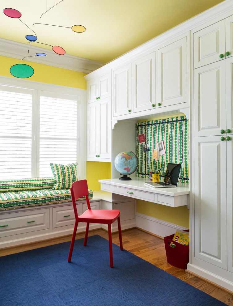Exempel på ett litet klassiskt könsneutralt barnrum kombinerat med skrivbord, med mellanmörkt trägolv och gula väggar
