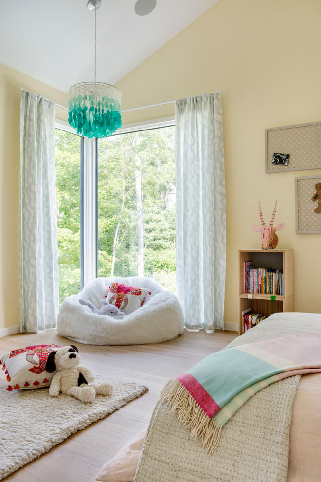 Design ideas for a large contemporary children’s room for girls in Boston with yellow walls and light hardwood flooring.