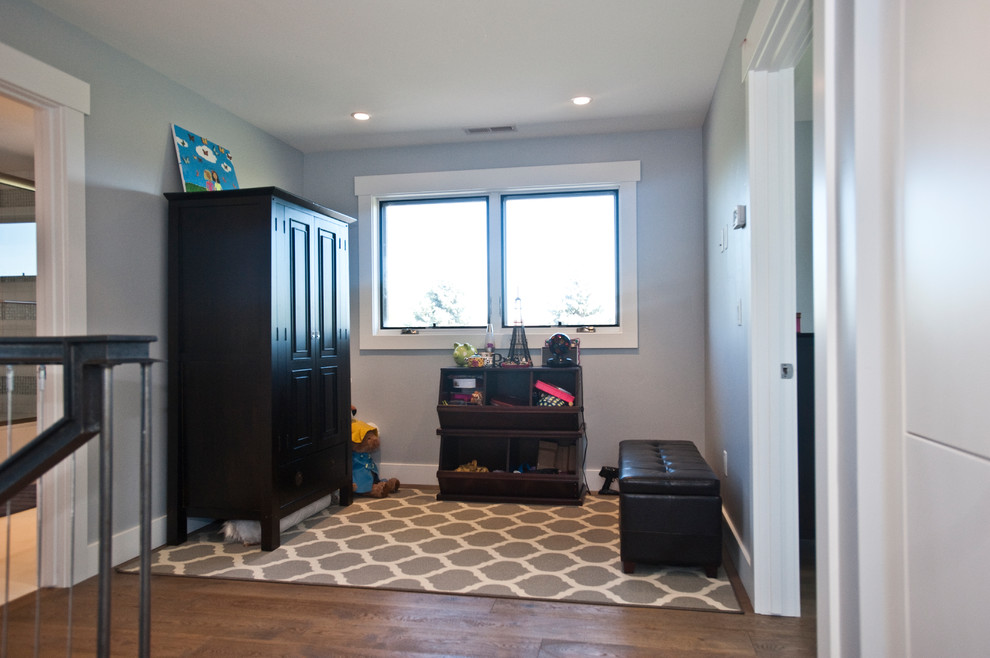 Large contemporary gender neutral kids' bedroom in Other with grey walls, medium hardwood flooring and brown floors.