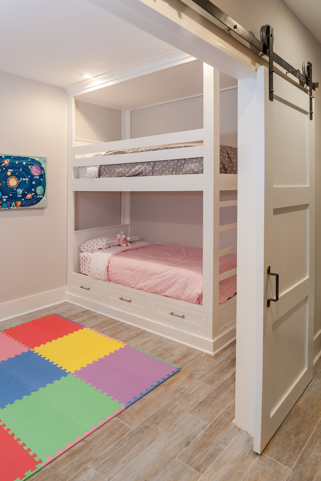 This is an example of a medium sized traditional children’s room for girls in New York with pink walls and light hardwood flooring.