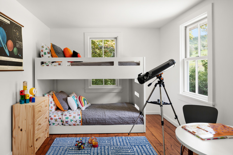 Immagine di una cameretta per bambini da 4 a 10 anni country di medie dimensioni con pareti bianche, pavimento in legno massello medio e pavimento marrone