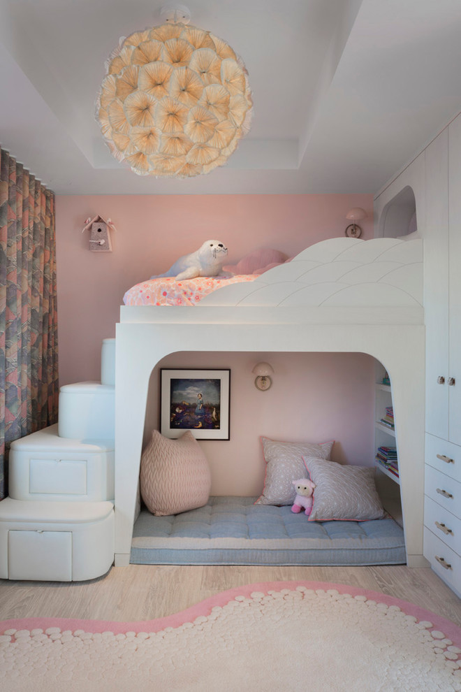 Photo of a retro children’s room for girls in Other with pink walls, light hardwood flooring and beige floors.