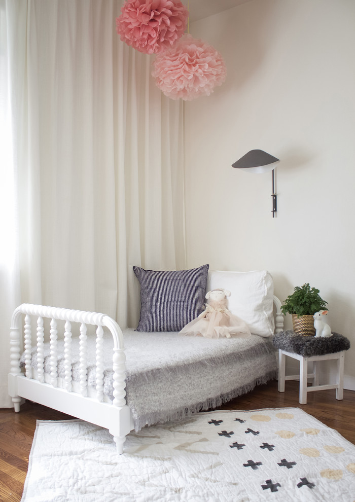 Foto på ett minimalistiskt barnrum kombinerat med sovrum, med vita väggar och mellanmörkt trägolv