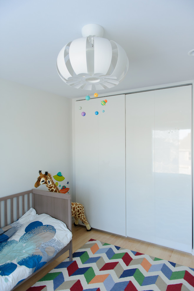 Example of a trendy gender-neutral light wood floor kids' room design in Other with white walls