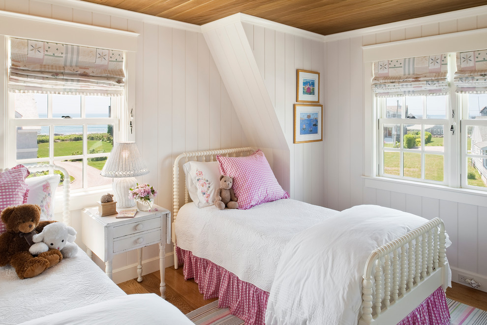 This is an example of a medium sized nautical children’s room for girls in Providence with white walls and medium hardwood flooring.