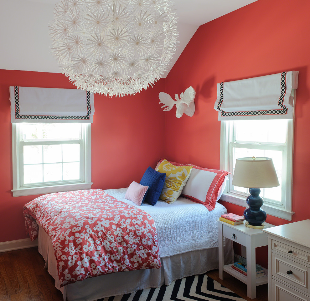 Cette image montre une petite chambre d'enfant bohème avec parquet foncé et un mur rouge.