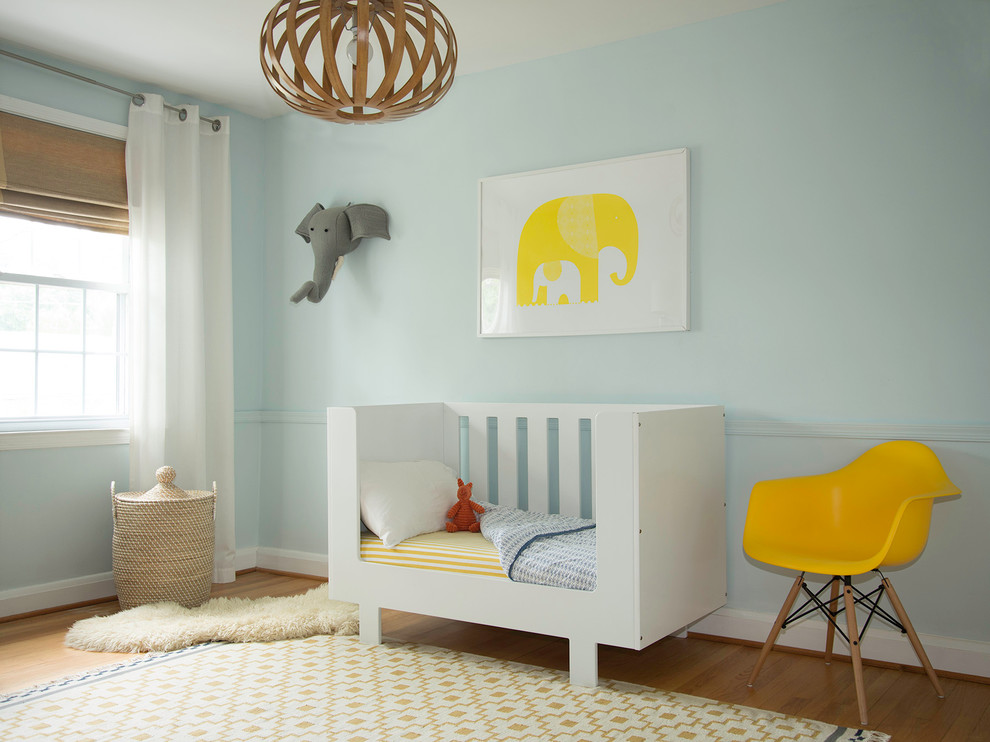 Idées déco pour une chambre d'enfant de 1 à 3 ans moderne de taille moyenne avec un mur bleu et un sol en bois brun.
