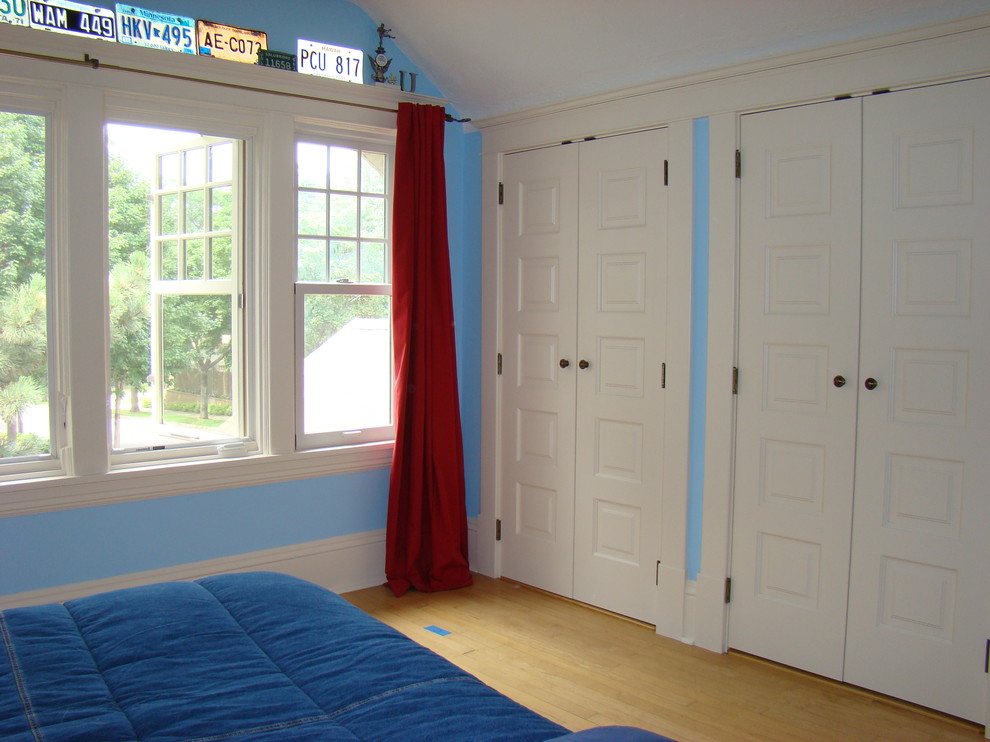 Imagen de dormitorio infantil clásico de tamaño medio con paredes azules y suelo de madera clara