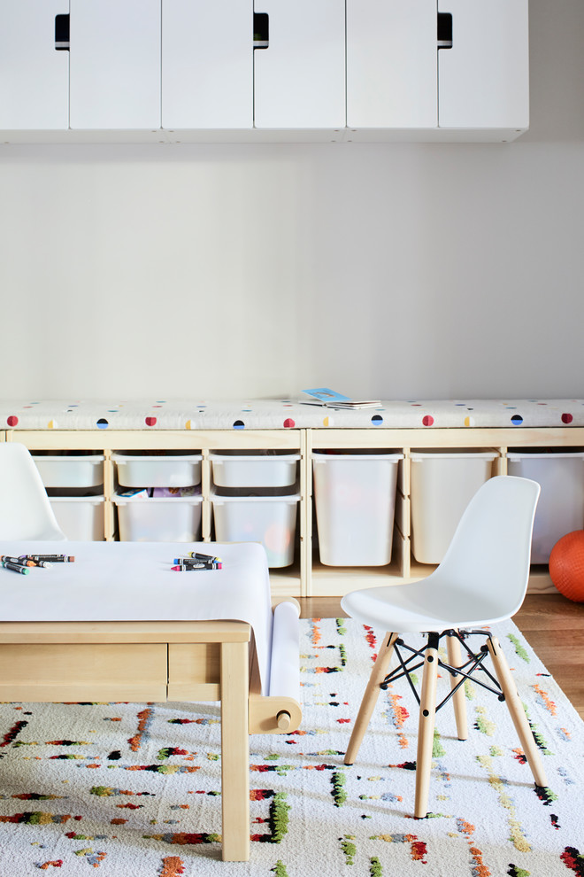 Inredning av ett modernt mellanstort könsneutralt småbarnsrum kombinerat med lekrum, med beige väggar, mellanmörkt trägolv och brunt golv