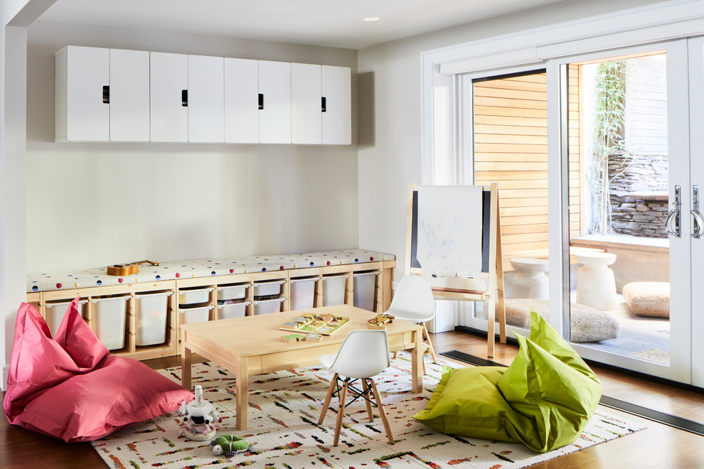 Idéer för mellanstora skandinaviska könsneutrala småbarnsrum kombinerat med lekrum, med beige väggar, mellanmörkt trägolv och brunt golv