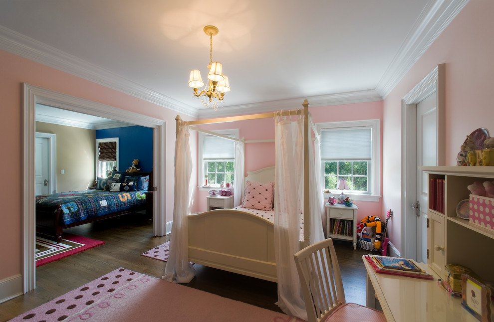 Large classic children’s room for girls in New York with pink walls and dark hardwood flooring.