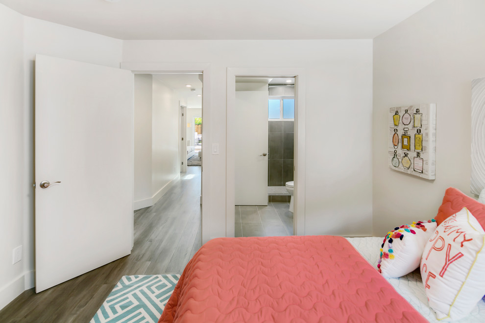 This is an example of a medium sized modern children’s room for girls in San Francisco with white walls and laminate floors.