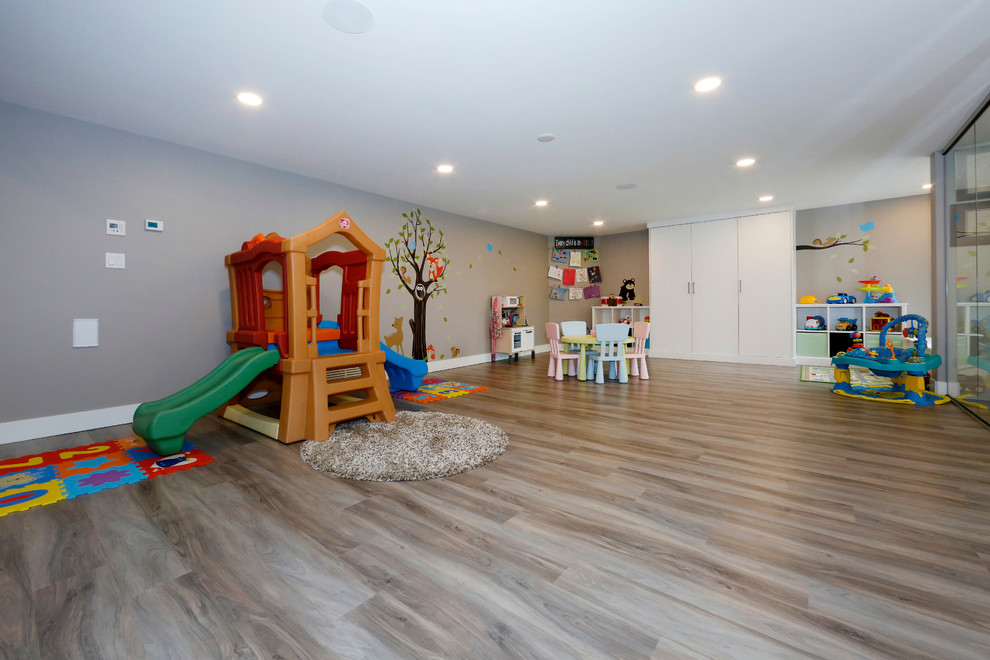 Exemple d'une grande chambre d'enfant de 1 à 3 ans tendance avec un mur gris et un sol en bois brun.