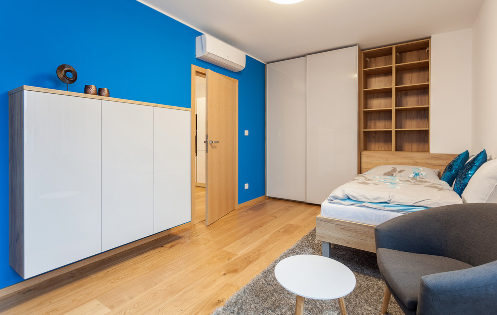 Immagine di una cameretta per bambini design di medie dimensioni con pareti blu e pavimento in compensato