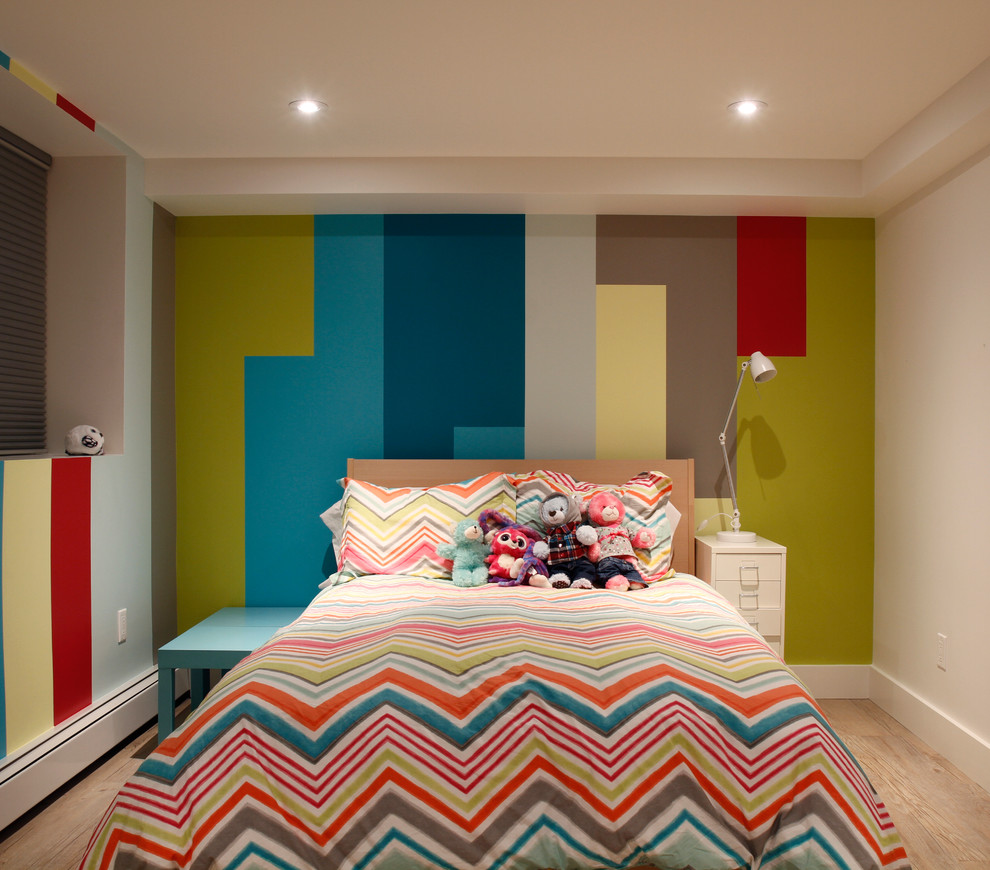 Inredning av ett modernt litet könsneutralt barnrum kombinerat med sovrum och för 4-10-åringar, med flerfärgade väggar och ljust trägolv