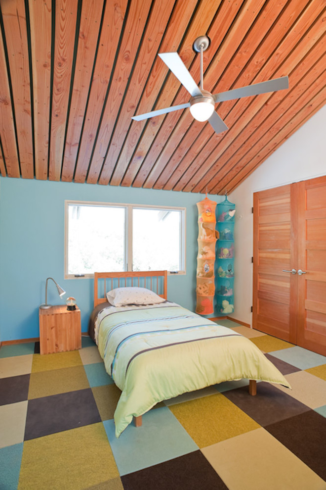 На фото: нейтральная детская в современном стиле с спальным местом, синими стенами и ковровым покрытием для ребенка от 4 до 10 лет