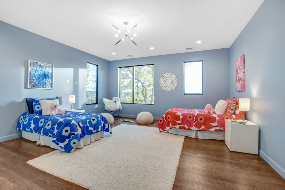 Esempio di una grande cameretta per bambini da 4 a 10 anni minimal con pareti blu, pavimento in legno massello medio e pavimento marrone