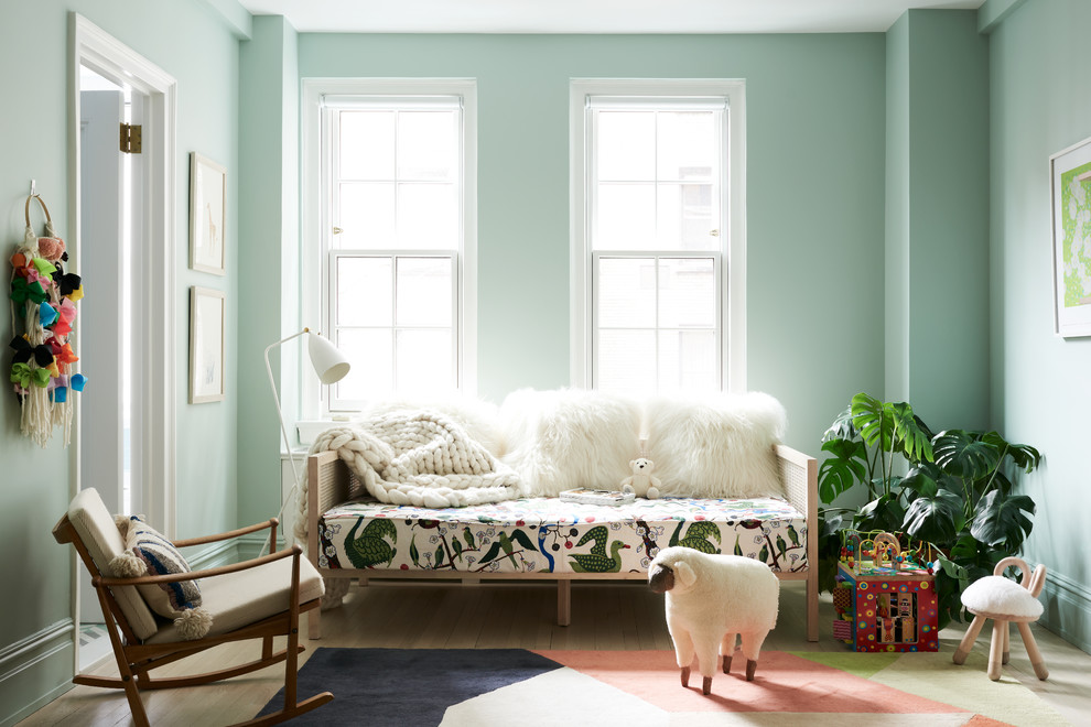 Immagine di una cameretta per bambini da 1 a 3 anni contemporanea di medie dimensioni con pareti verdi, parquet chiaro e pavimento beige