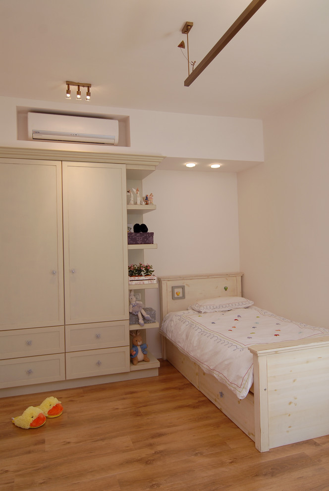 Immagine di una cameretta per bambini design con pareti beige e pavimento in legno massello medio