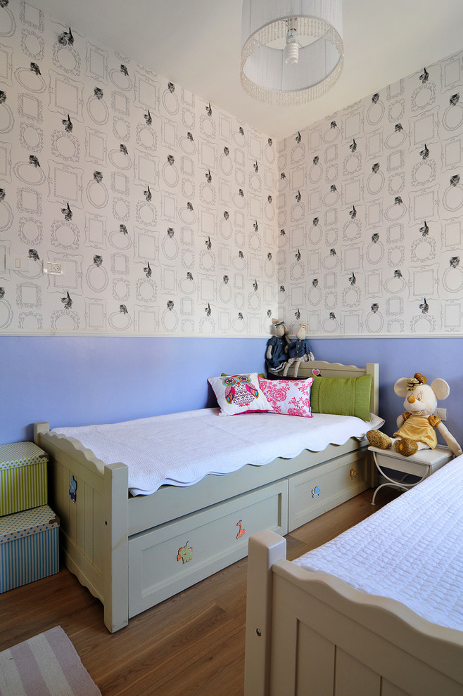 Inspiration for a contemporary children’s room for girls in Tel Aviv with multi-coloured walls and medium hardwood flooring.