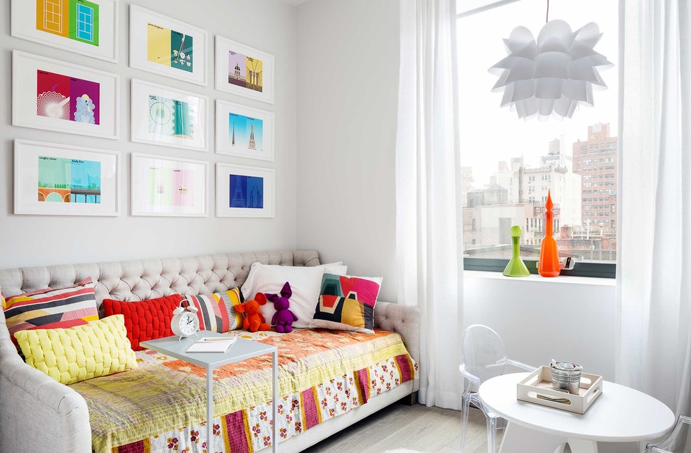 This is an example of a contemporary kids' bedroom in New York with white walls and light hardwood flooring.