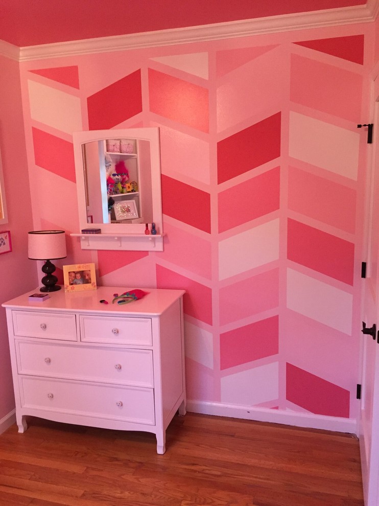 Réalisation d'une petite chambre d'enfant de 4 à 10 ans bohème avec un mur rose et un sol en bois brun.