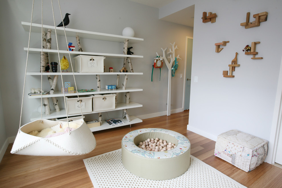 Medium sized scandi gender neutral kids' bedroom in New York with grey walls and light hardwood flooring.
