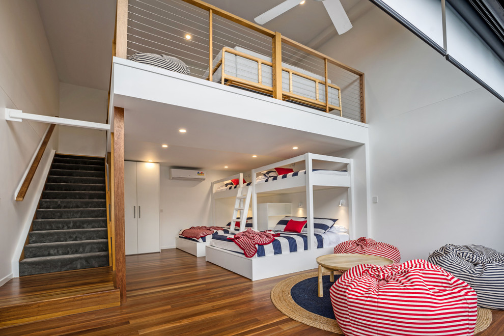 Imagen de dormitorio infantil costero de tamaño medio con paredes blancas, suelo de madera en tonos medios y suelo marrón