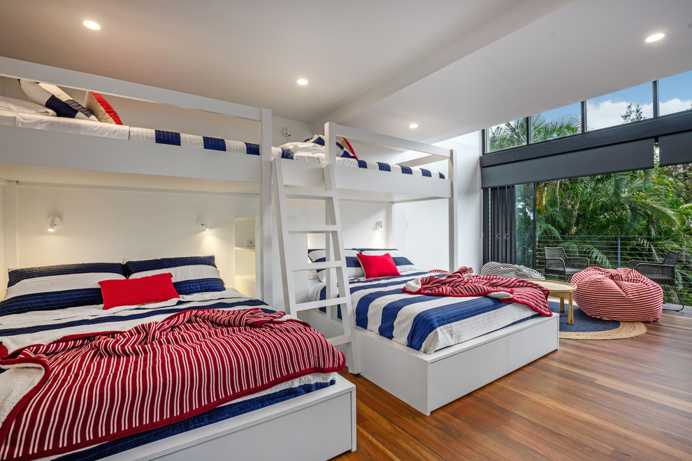 Esempio di una cameretta per bambini costiera di medie dimensioni con pareti bianche, pavimento in legno massello medio e pavimento marrone