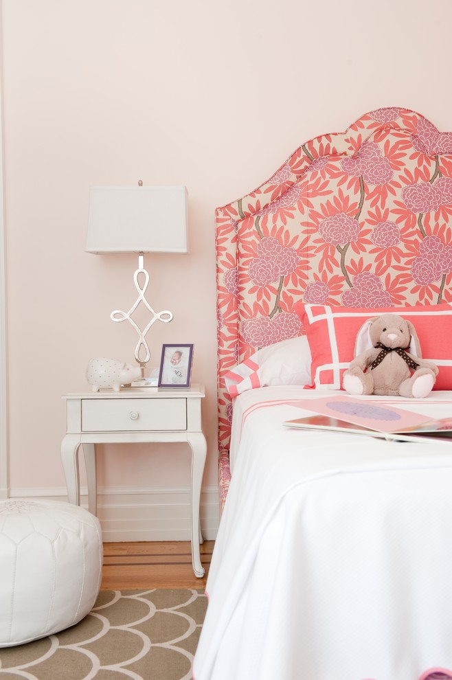 This is an example of a medium sized classic children’s room for girls in Miami with pink walls and light hardwood flooring.