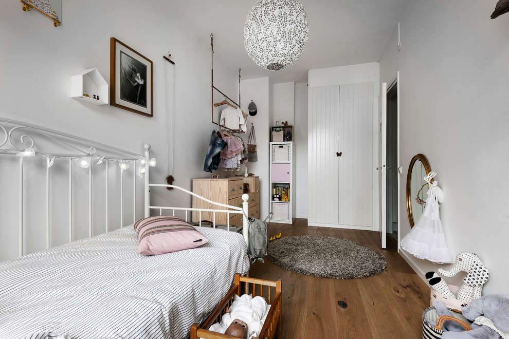 Scandi kids' bedroom in San Francisco with white walls, medium hardwood flooring and brown floors.