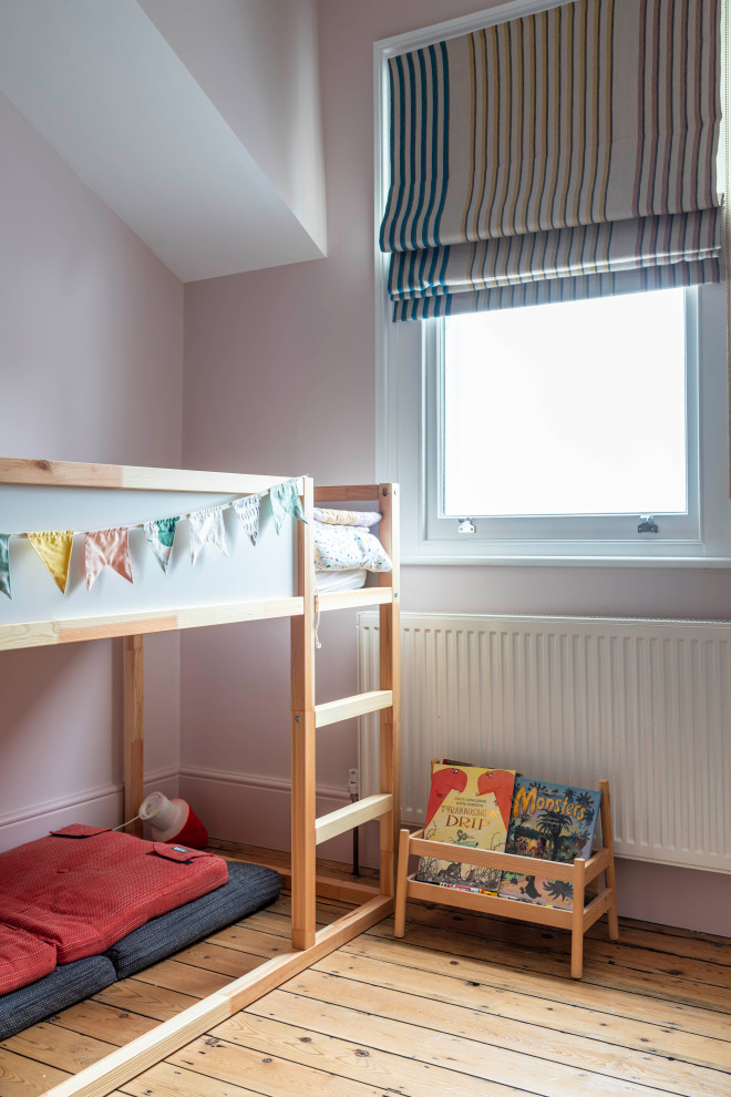 Photo of a scandi kids' bedroom in London with pink walls, light hardwood flooring and beige floors.