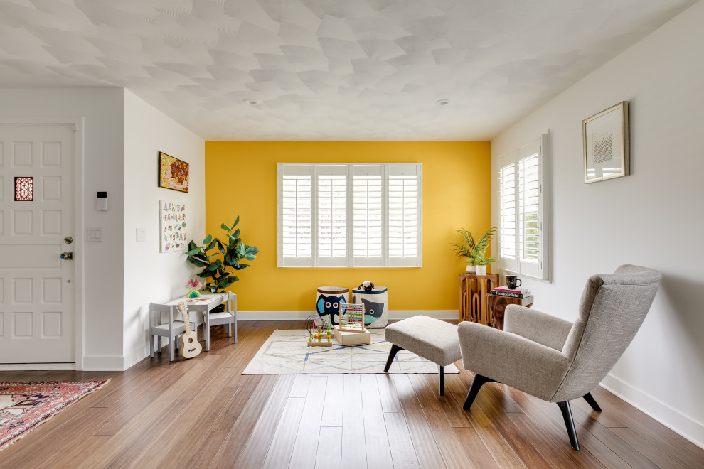 Immagine di una cameretta per bambini da 1 a 3 anni classica con pareti gialle, pavimento in legno massello medio e pavimento marrone