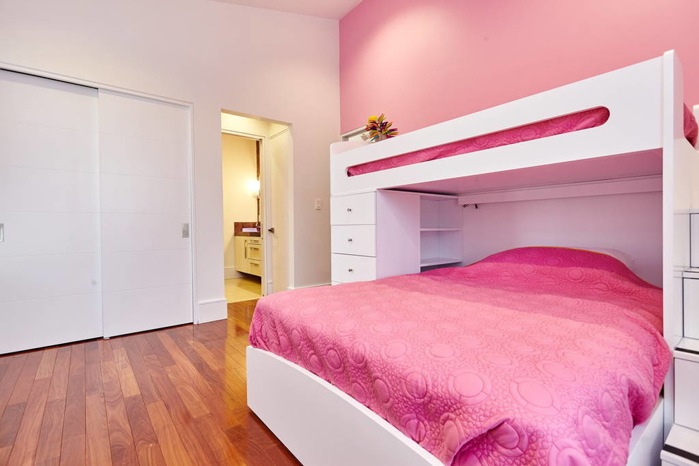 Aménagement d'une grande chambre d'enfant de 4 à 10 ans moderne avec un mur rose et un sol en bois brun.