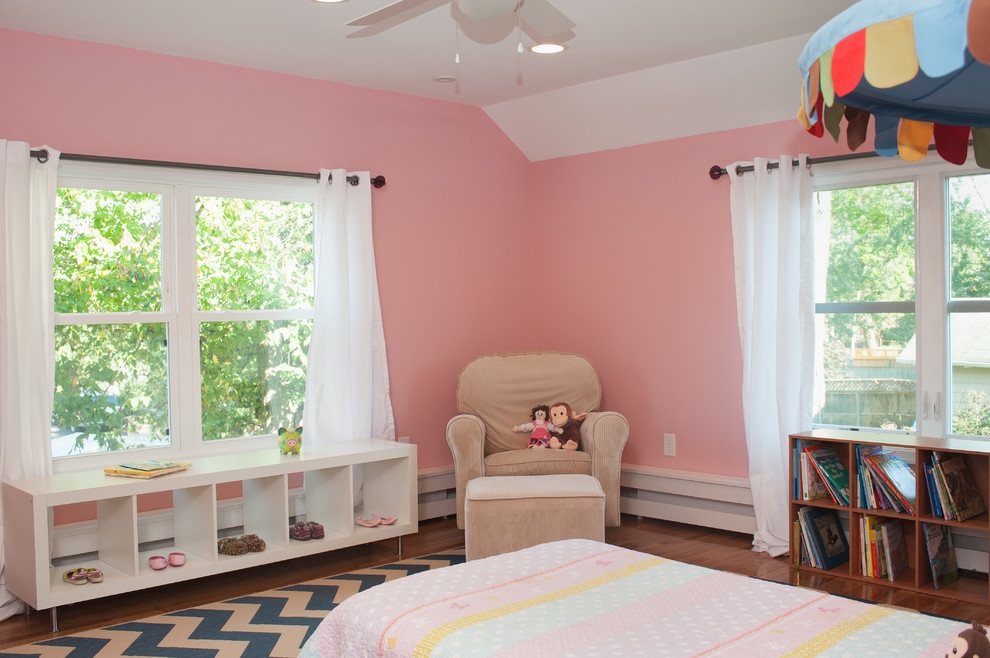 Réalisation d'une grande chambre d'enfant de 4 à 10 ans tradition avec un mur rose, un sol en bois brun et un sol marron.