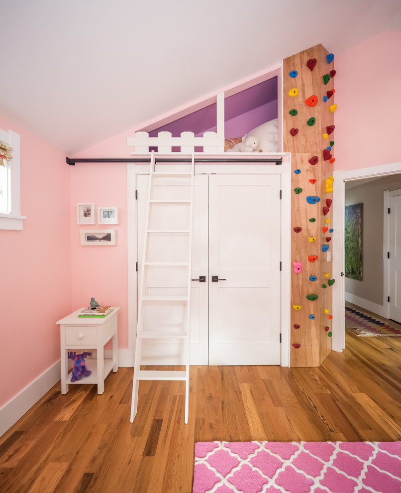 Modelo de dormitorio infantil blanco clásico renovado de tamaño medio con paredes rosas, suelo de madera clara y suelo marrón