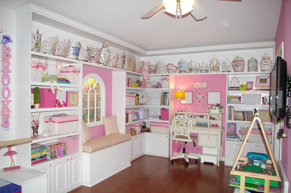 Modelo de habitación de niña de 4 a 10 años tradicional de tamaño medio con escritorio, paredes rosas y suelo de madera en tonos medios