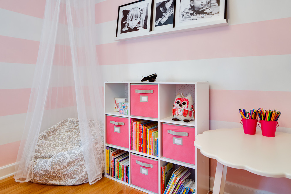 Réalisation d'une chambre de fille de 1 à 3 ans design avec un bureau, un sol en bois brun et un mur multicolore.