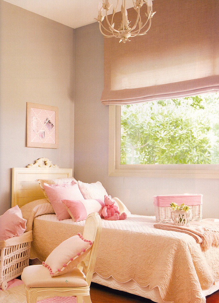 This is an example of a small romantic children’s room for girls in Madrid with grey walls and dark hardwood flooring.