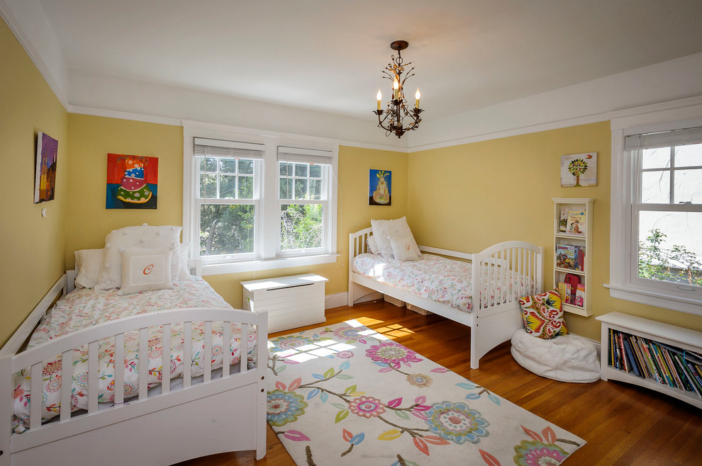На фото: детская в классическом стиле с желтыми стенами для двоих детей с