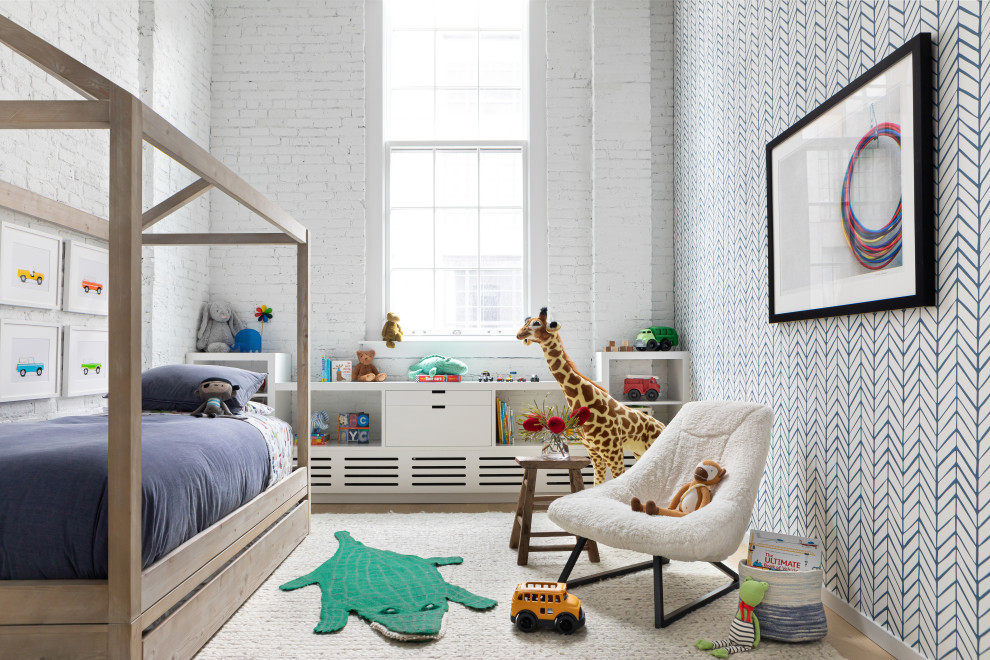This is an example of a large contemporary toddler’s room for boys in New York with white walls, light hardwood flooring and brown floors.